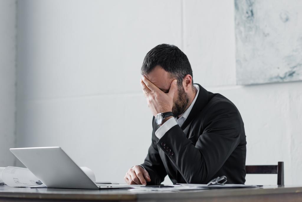 расстроен бизнесмен, держась за лицо, сидя на рабочем месте
 - Фото, изображение