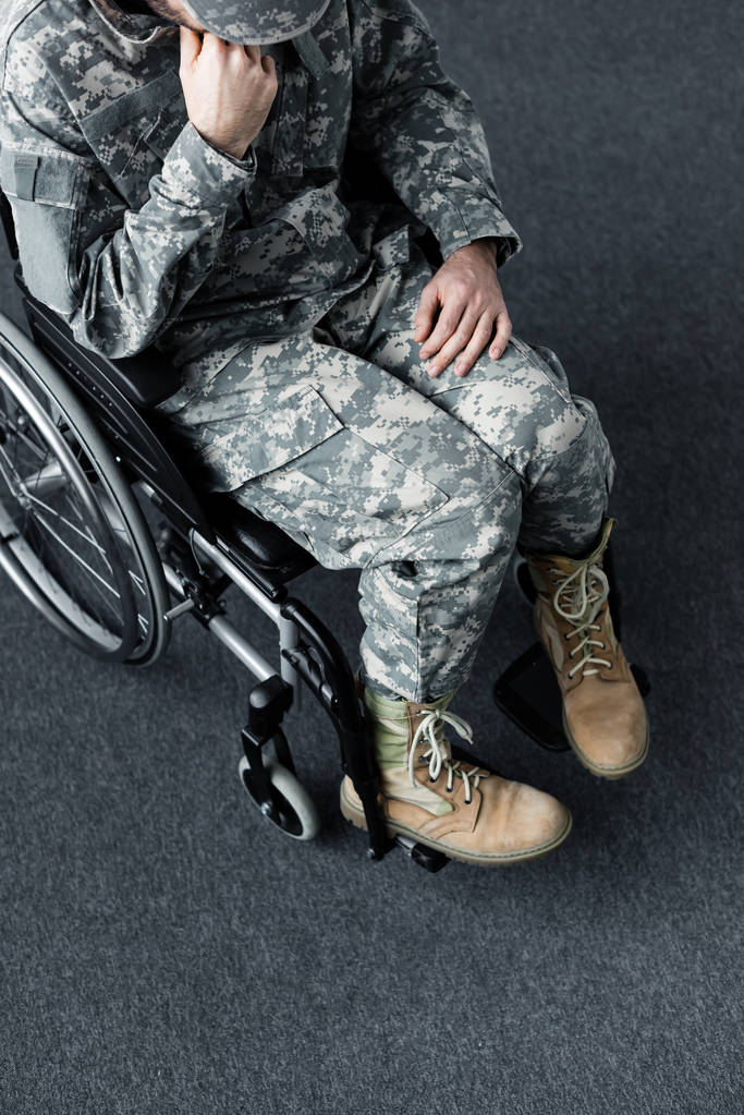 вид сверху на инвалида в военной форме, сидящего в инвалидной коляске с наклоненной головой
 - Фото, изображение