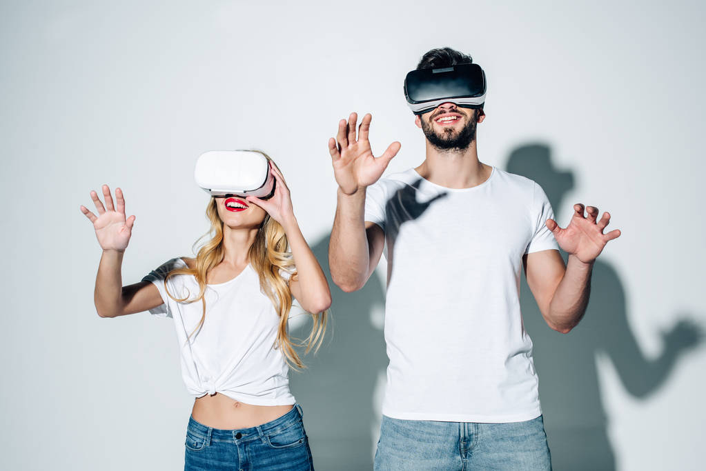 hombre y mujer alegres en auriculares de realidad virtual gestos en blanco
  - Foto, imagen