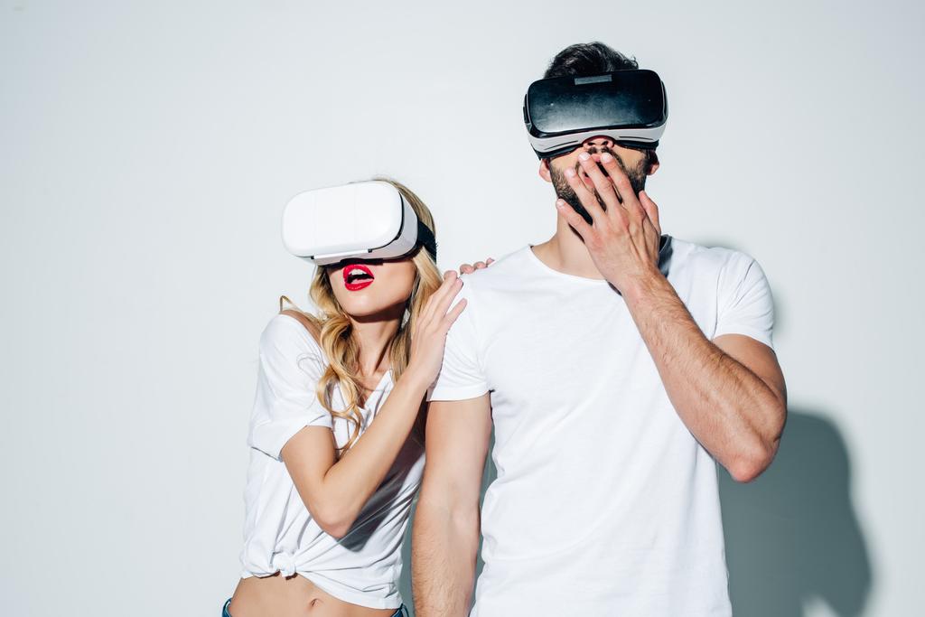 удивленные мужчина и женщина в наушниках виртуальной реальности на белом
  - Фото, изображение