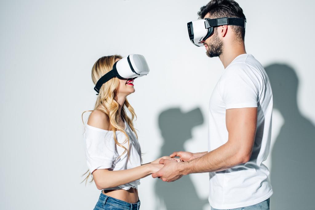 hombre feliz cogido de la mano con la mujer rubia mientras usa auriculares de realidad virtual en blanco
  - Foto, imagen
