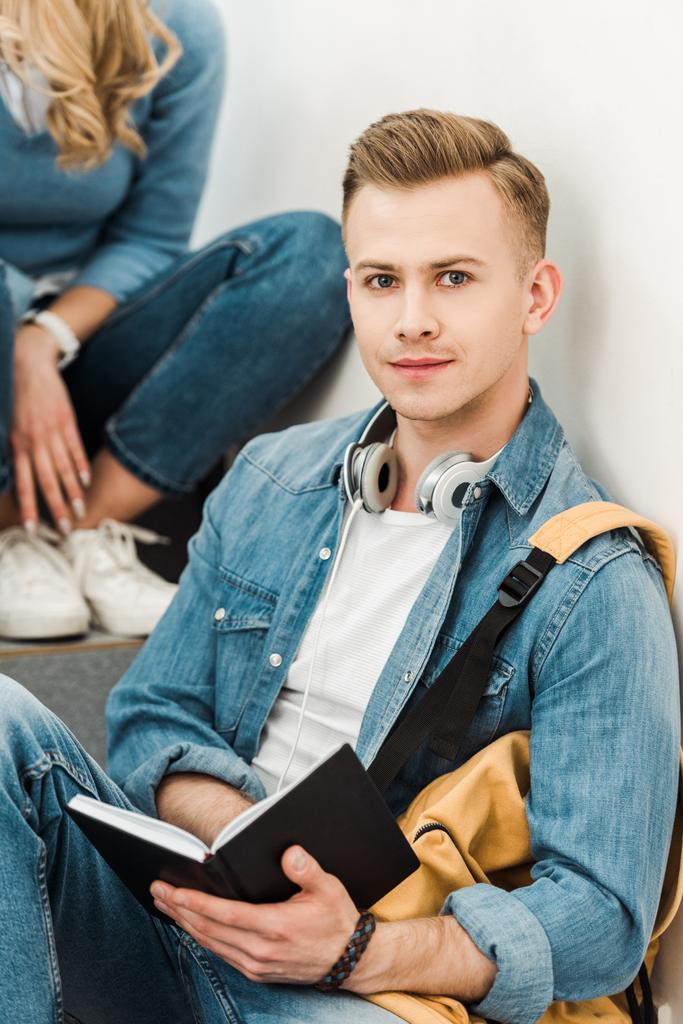 étudiant en jeans chemise tenant livre et regardant la caméra
 - Photo, image