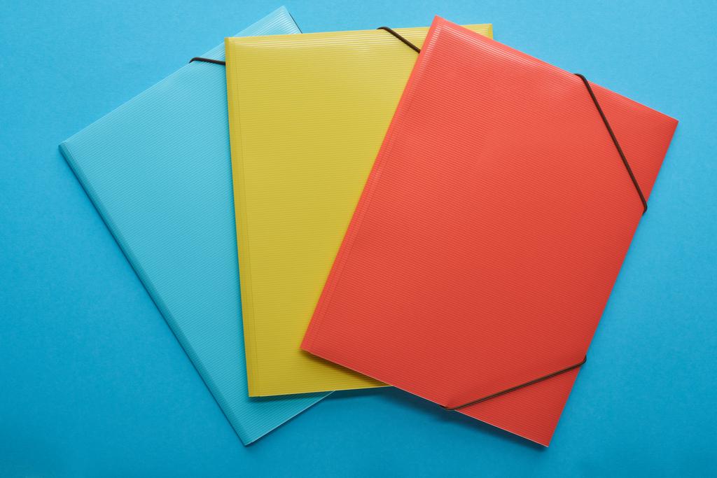 Ansicht von roten, blauen und gelben Papierordnern isoliert auf blau - Foto, Bild