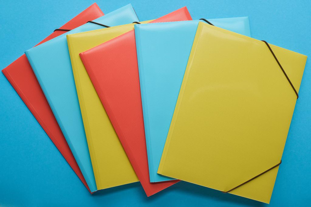 Κορυφαία όψη των πολύχρωμων ντοσιέ χαρτιού γραφείου στο μπλε - Φωτογραφία, εικόνα