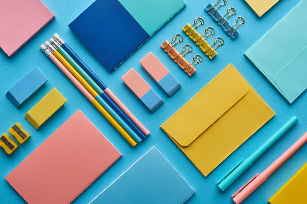 vista superior de cuadernos y papelería colorida arreglada aislada en azul
 - Foto, Imagen