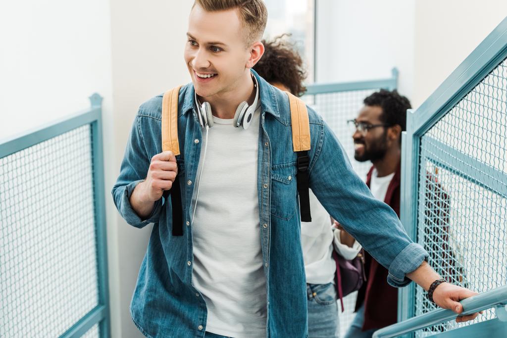 усміхнені багатоетнічні студенти з рюкзаками на сходах в коледжі
 - Фото, зображення