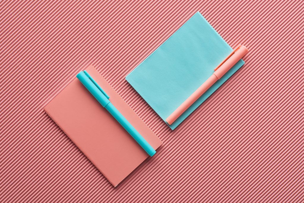 vista superior de bolígrafos y cuadernos en rosa texturizado
 - Foto, imagen