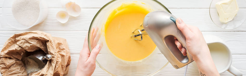 prise de vue panoramique de la pâte à mélanger femme avec mélangeur à main sur table en bois
 - Photo, image