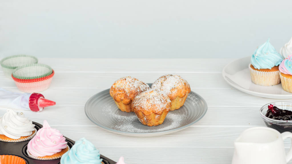 heerlijke cupcakes en muffins op witte houten tafel geïsoleerd op grijs - Foto, afbeelding