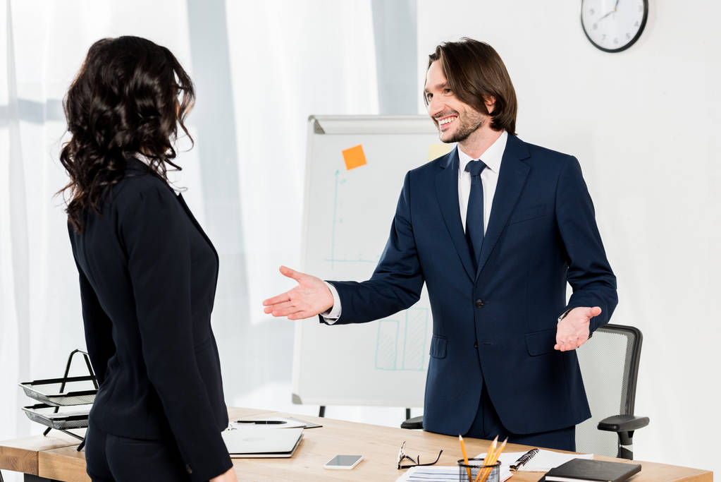 knappe recruiter gebaren in de buurt van brunette vrouw in Office  - Foto, afbeelding