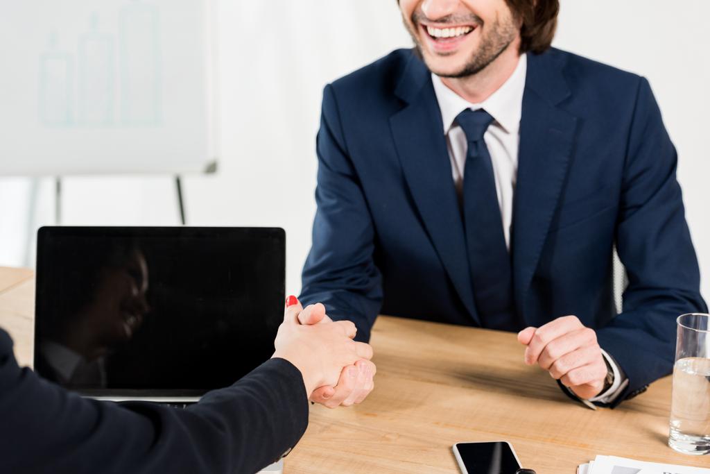 vista recortada de hombre alegre estrechando la mano con reclutador en la oficina
  - Foto, imagen