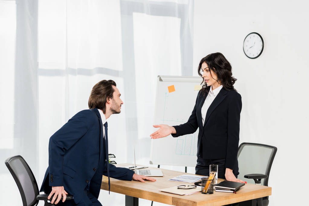 atractivo reclutador gesto mientras está de pie cerca de hombre en la oficina
  - Foto, Imagen