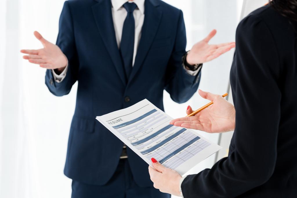 cropped view of woman holding resume and pencil near gesturing man  - Photo, Image