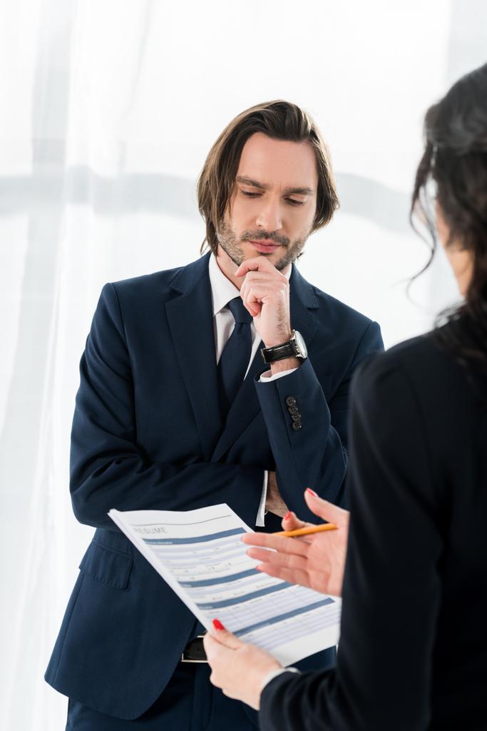selective focus of pensive man standing near brunette woman with resume in hands  - Photo, Image