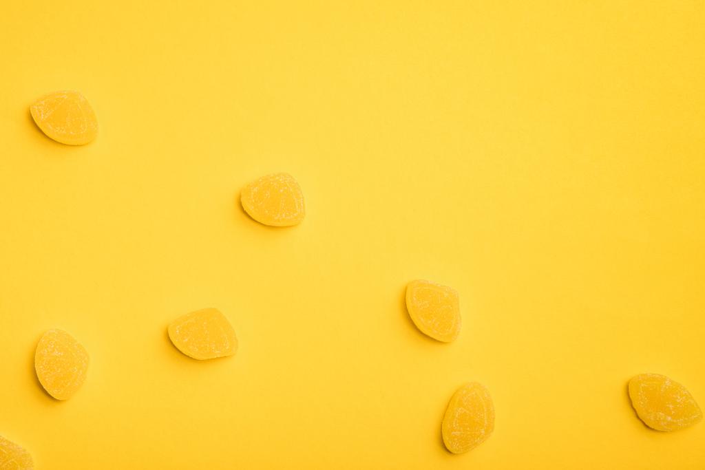 黄色の背景に散らばったおいしい甘いゼリーのトップビュー - 写真・画像