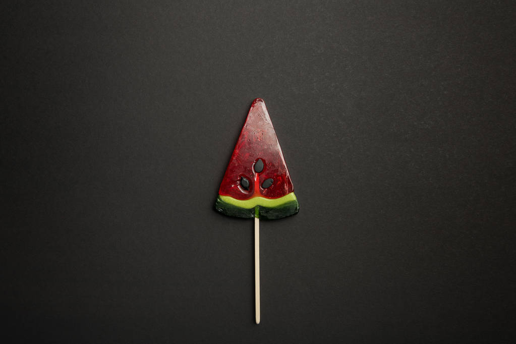 Top uitzicht van watermeloen smakelijke Lollipop op houten stok op zwarte achtergrond - Foto, afbeelding