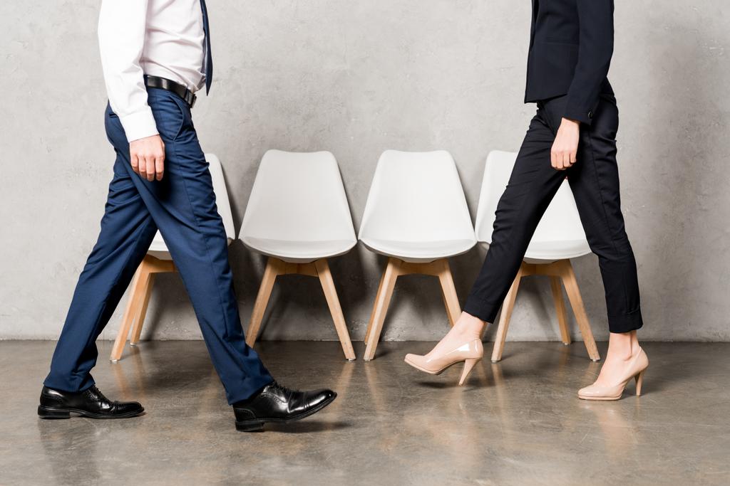обрізаний вид чоловіка і жінки в офіційному одязі, що ходить в офісі
  - Фото, зображення