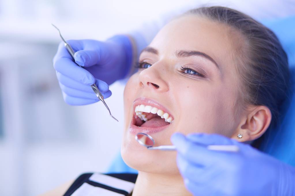 Jonge vrouwelijke patiënt met open mond onderzoeken tandheelkundige inspectie op tandartspraktijk. - Foto, afbeelding