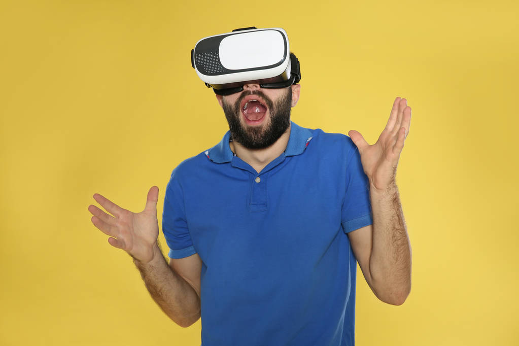 感情的な若い男は、色の背景にバーチャルリアリティヘッドセットでビデオゲームをプレイ - 写真・画像