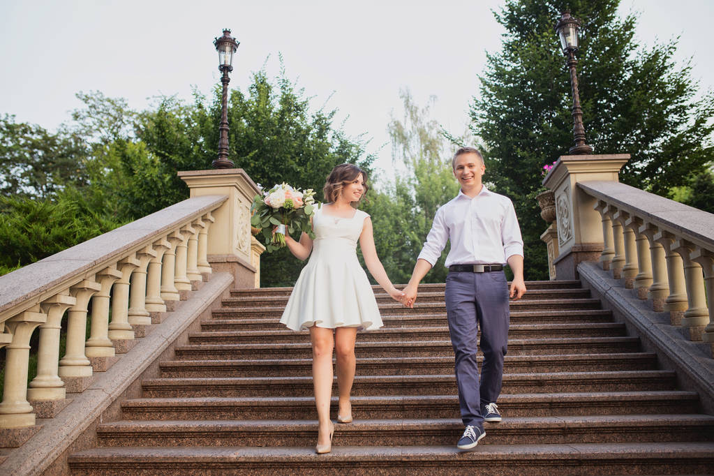 молода наречена і наречений позує на фоні цементних мармурових сходів
 - Фото, зображення