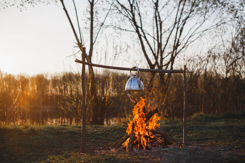 Teapot s čajem visí nad ohněm na slunci na břehu řeky - Fotografie, Obrázek