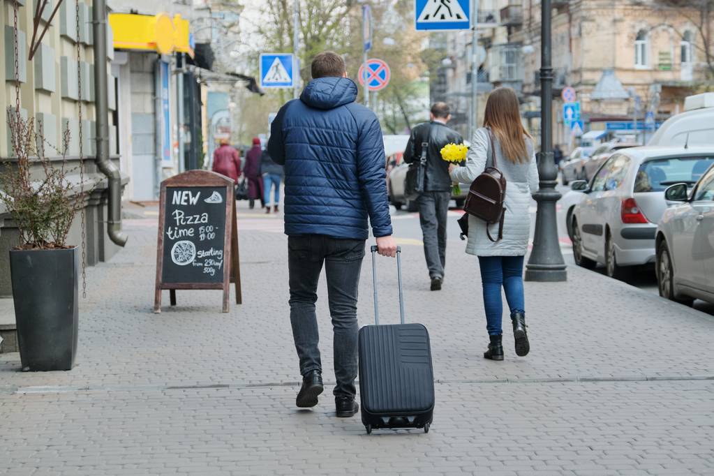 Hombre de chaqueta con maleta caminando por la calle de la ciudad, vista trasera
 - Foto, imagen