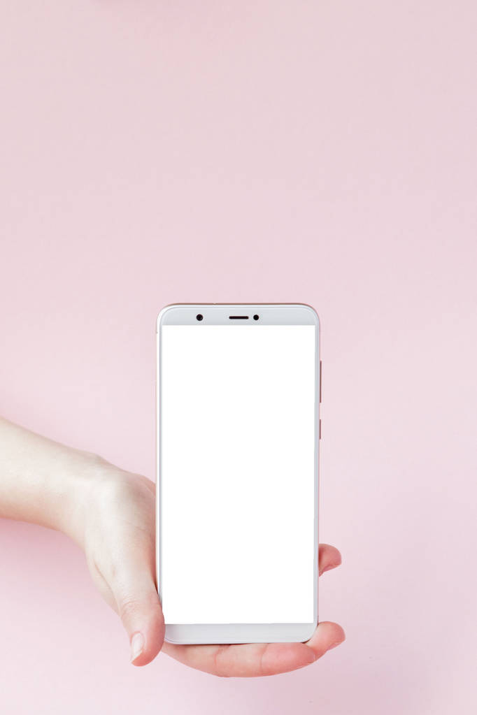ピンクの背景に女性の手で現代の携帯電話 - 写真・画像