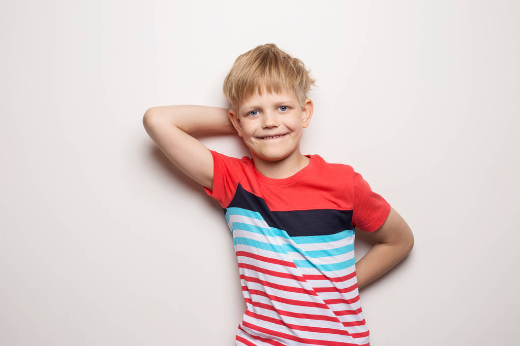 Маленький улыбающийся мальчик в футболке на белом фоне. Студийный портрет
 - Фото, изображение