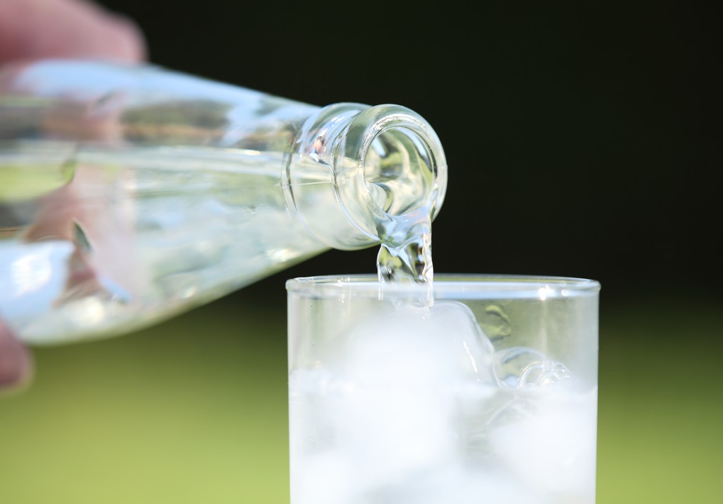 Close-up van fles met stromende water - Foto, afbeelding