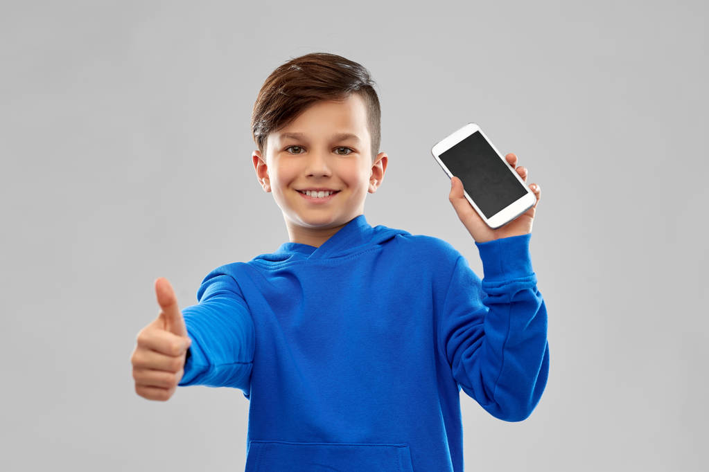 スマートフォンと親指を上に示す笑顔の少年 - 写真・画像