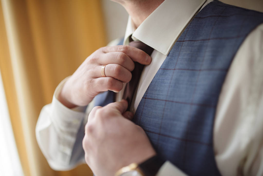 Чоловік у костюмі вирівнює краватку
 - Фото, зображення