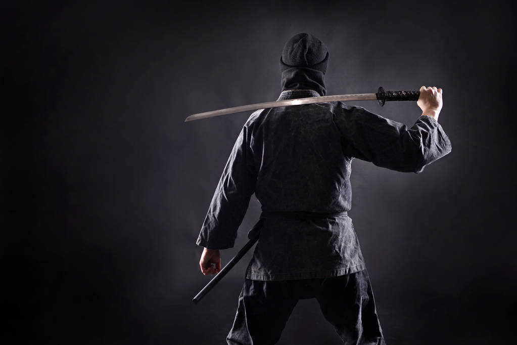Ninja samurai con katana se para con su espalda al espectador
. - Foto, imagen