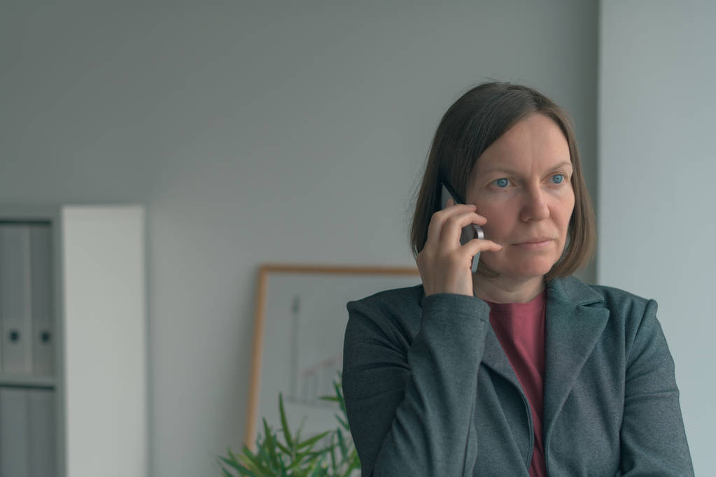 Donna d'affari seria che parla al cellulare in ufficio
 - Foto, immagini