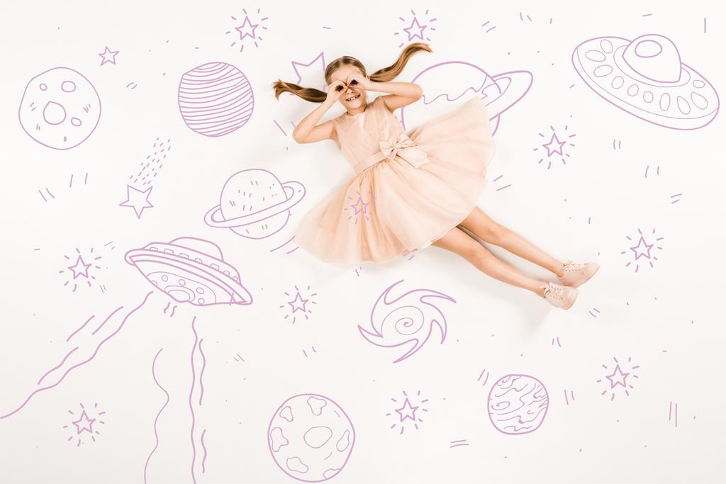 visão superior da criança alegre no vestido rosa com mãos perto de olhos no espaço no branco
  - Foto, Imagem