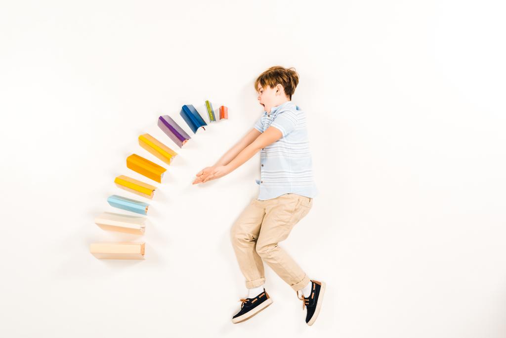 vista superior da criança surpreso perto de livros coloridos em branco
  - Foto, Imagem
