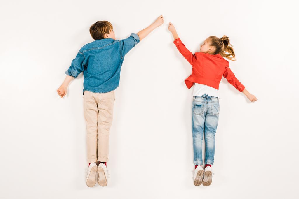 Top uitzicht van schattige kinderen gebaren terwijl liggend op wit  - Foto, afbeelding