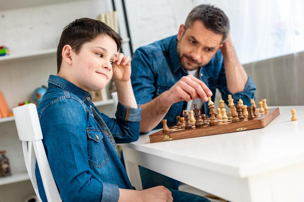 padre e figlio in denim che giocano a scacchi seduti a tavola a casa
 - Foto, immagini