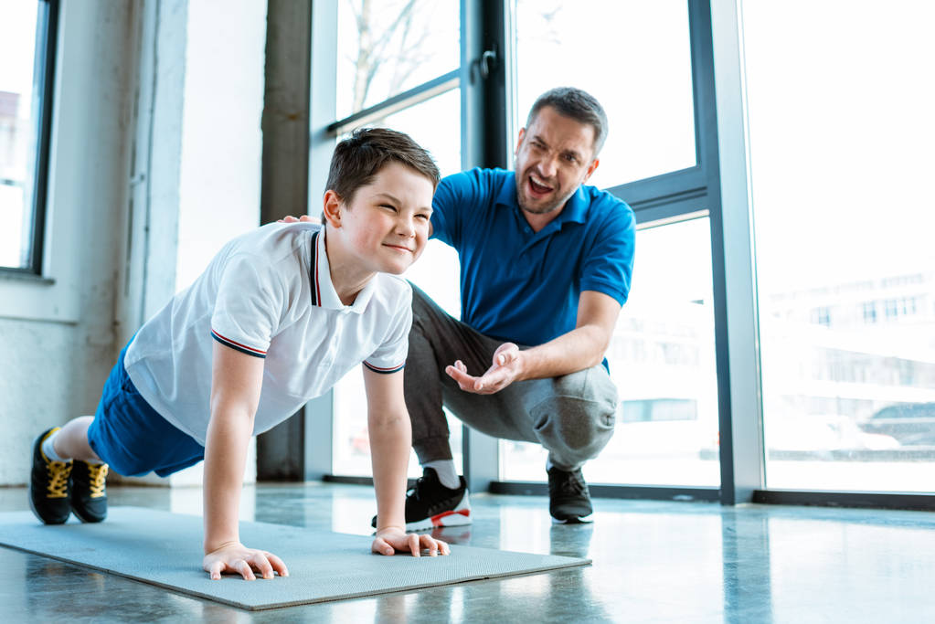 padre ayudando hijo con push up ejercicio en el gimnasio
 - Foto, imagen