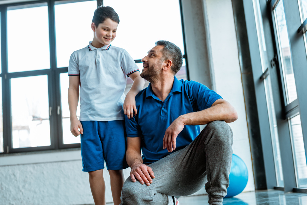 usmívající se otec a syn se na sebe dívají ve sportovním centru - Fotografie, Obrázek