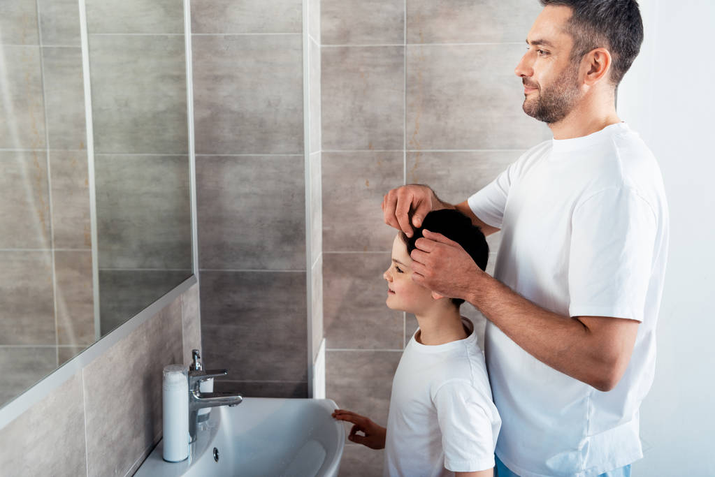 отец регулирует прическу сына в ванной комнате утром
 - Фото, изображение