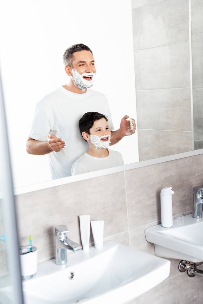 boldog apa alkalmazó borotválkozó krém arcán fia fürdőszoba reggel - Fotó, kép