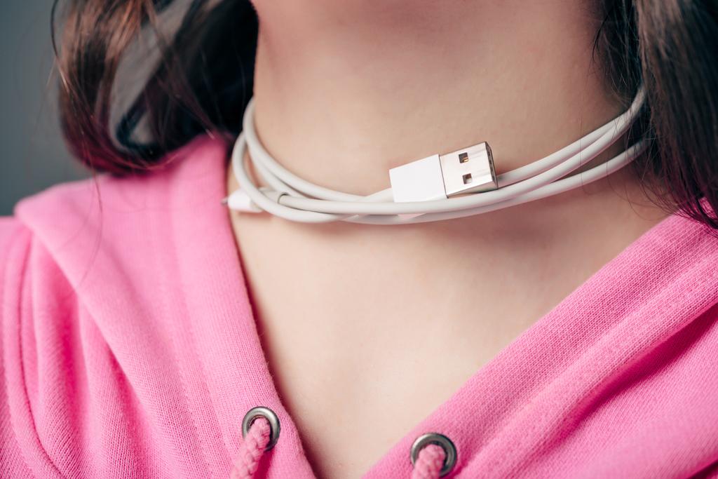 gedeeltelijke weergave van jong vrouwtje met USB-kabel op kneck geïsoleerd op grijs - Foto, afbeelding