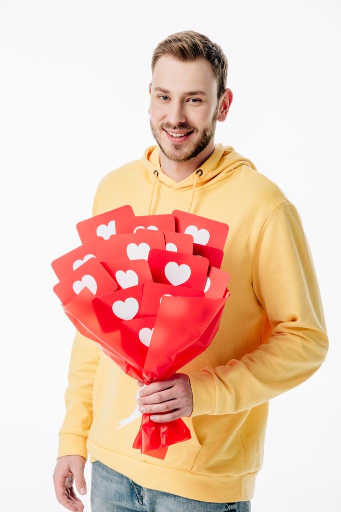 knappe vrolijke man Holding boeket van rood papier knippen kaarten met harten symbolen en kijken naar camera geïsoleerd op wit - Foto, afbeelding