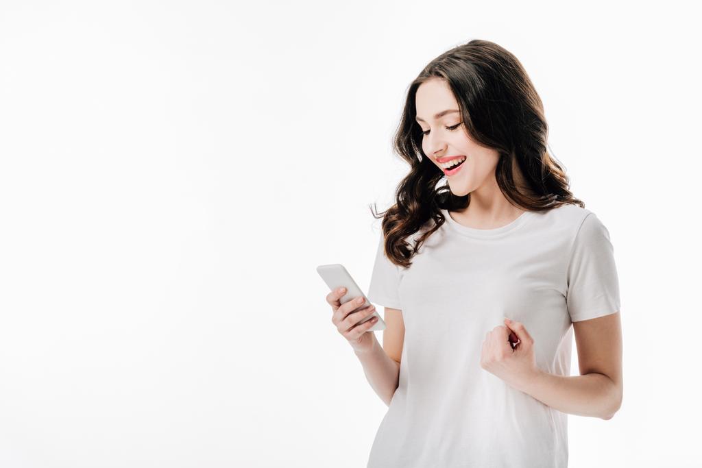 ziemlich fröhliches Mädchen im weißen T-Shirt mit Smartphone isoliert auf weiß - Foto, Bild