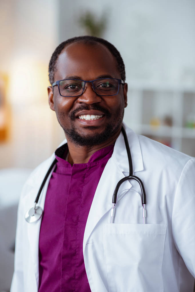 Красивый темнокожий доктор улыбается после хорошего дня на работе
 - Фото, изображение