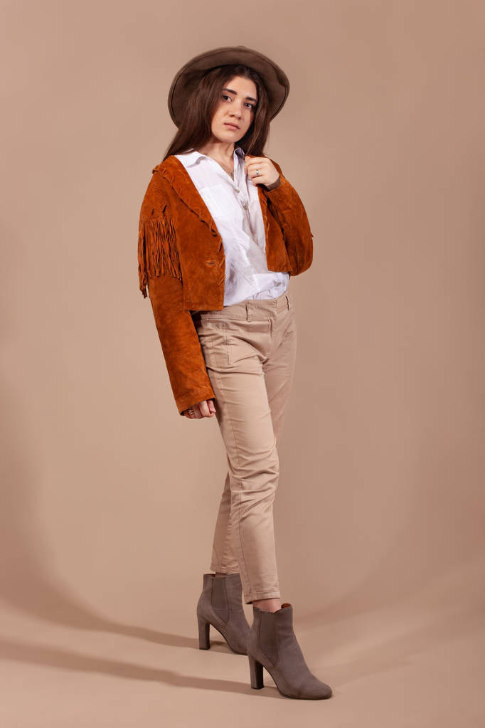 Woman wearing fashion clothes and hat on brown background. - Photo, Image