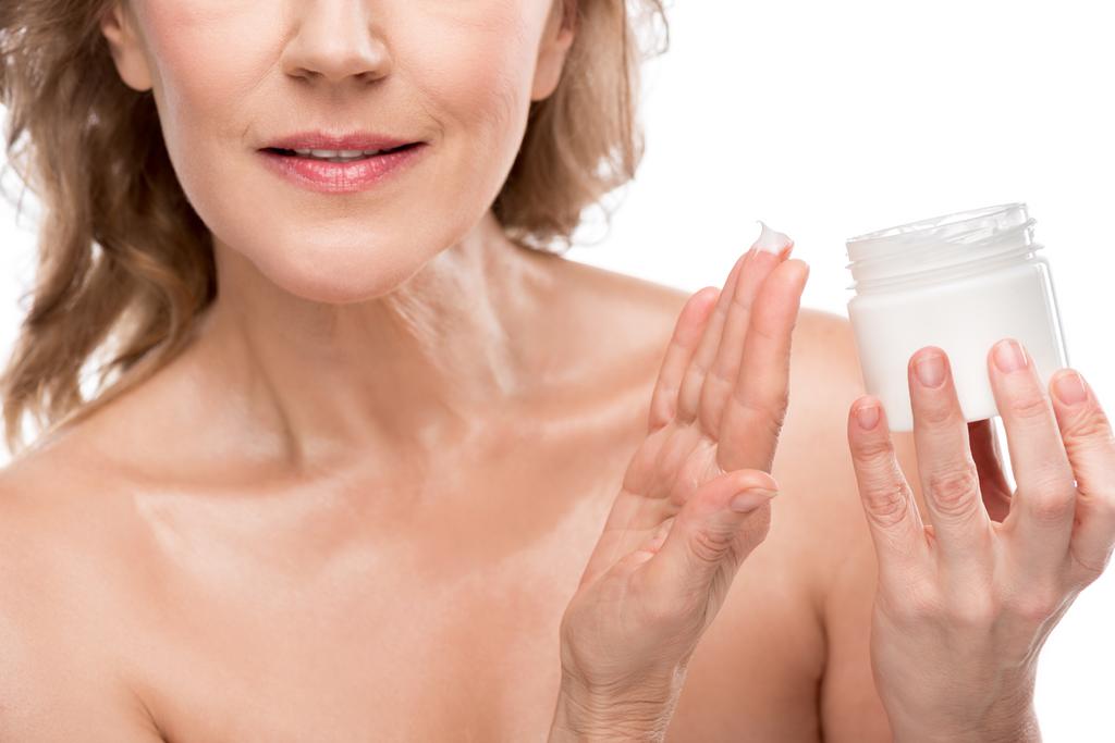 abgeschnittene Ansicht der reifen Frau mit perfekter Haut Aufbewahrungsbehälter mit kosmetischer Creme isoliert auf weiß - Foto, Bild