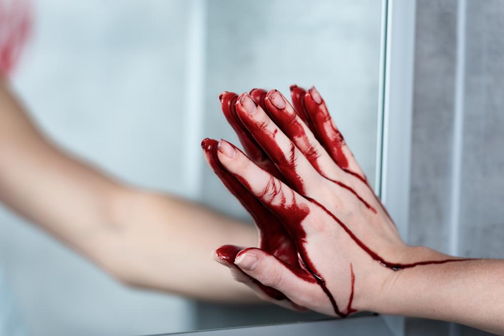 gedeeltelijke weergave van de vrouw met bloeden hand aanraken spiegel in de badkamer - Foto, afbeelding