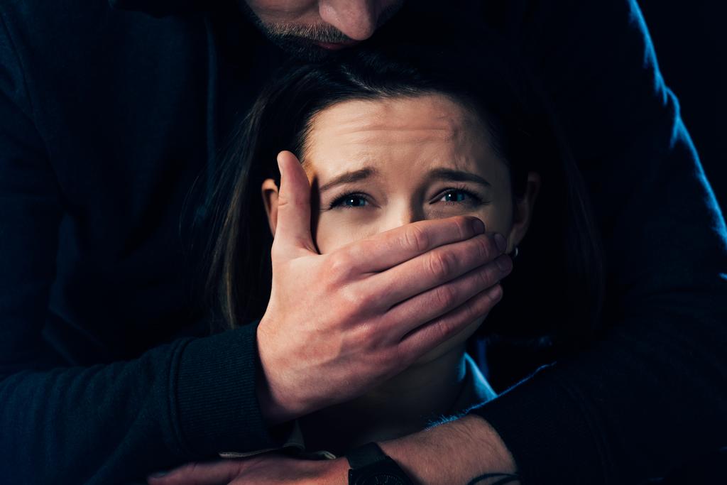 vue partielle de criminel attaquant femme effrayée et couvrant sa bouche isolé sur noir
 - Photo, image