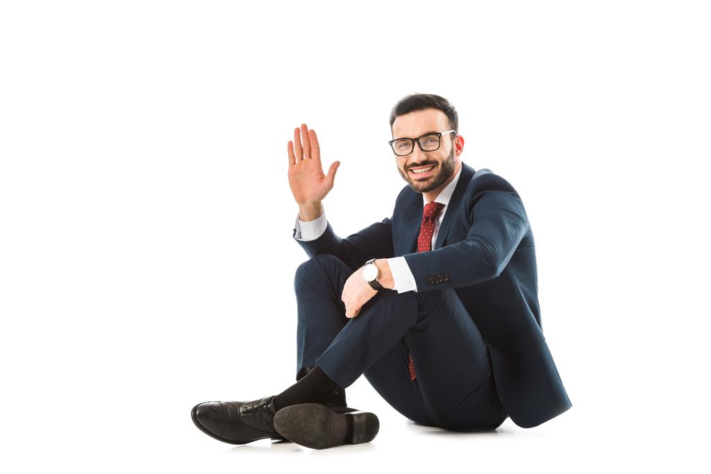 cheerful businessman showing hello gesture while sitting on white background - Photo, Image